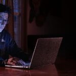 Seorang remaja sedang mengetik di laptop dengan cahaya biru lembut — simbol suara pertama yang muncul di dunia digital.